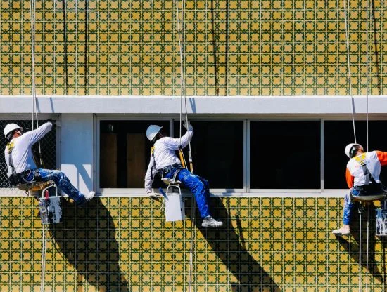 Rope access painter applying exterior coating to Dubai high-rise facade